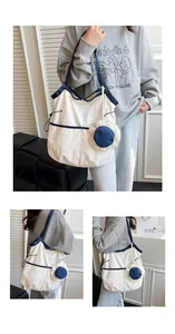 Detailed close-up of a large canvas tote bag featuring contrast trim and a mini pouch