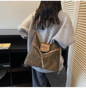 Detail of leopard print tote bag featuring brown leather trim and metal buckle accents