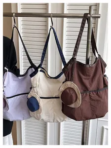 Three colors of large canvas tote bags with unique mini hat charms for daily commuting