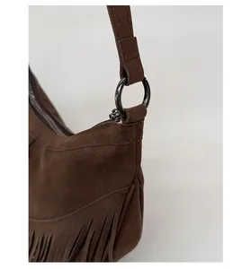 Détail du sac à franges en daim marron foncé avec des boucles métalliques rondes de qualité