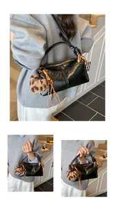 Detail of black glossy pillow bag featuring gold hardware and leopard print charm