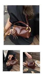 Detail of dark brown vintage crossbody bag with gold hardware and leopard charm