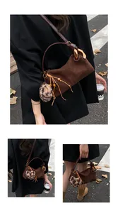 Detail of dark brown suede shoulder bag with leopard print charm and golden hardware