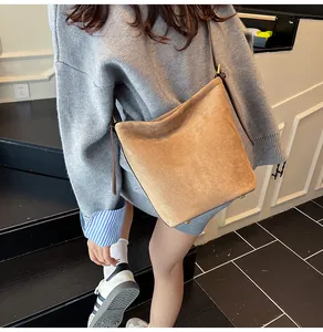 Chic camel suede bucket bag styled with a gray knit sweater and striped shirt on a model