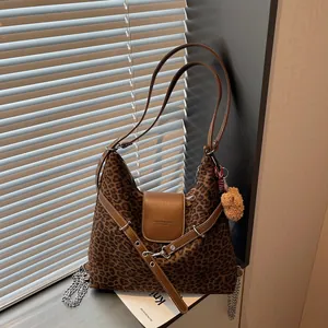 Retro leopard print tote bag with brown leather trim and bear pendant in sunlight