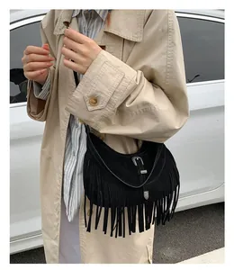 Détail d'un sac à franges noir bohème avec boucle western et texture en daim sur modèle