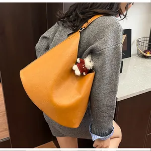 Detail of ginger faux leather crescent tote bag with cute teddy bear charm accessory