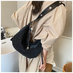 Detail of black matte crossbody bag with wide metal eyelet strap and fringe tassel