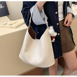 Close-up of beige leather tote bag with brown lining and plush puppy charm detail