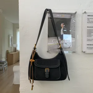 Close-up of black suede tote bag with contrast stitching and wooden bead tassel detail