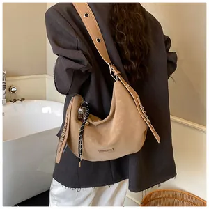 Close-up of khaki hobo bag with wide strap, metal eyelets, and braided rope charm