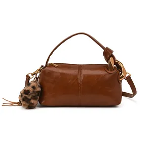 Brown leather barrel bag with gold chain handle and leopard print faux fur charm