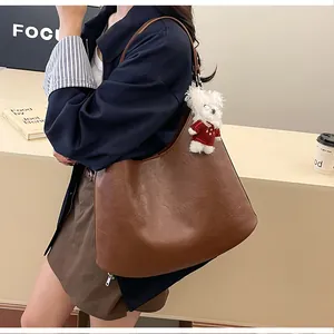 Detailed texture of brown faux leather tote bag featuring a cute white plush bear charm