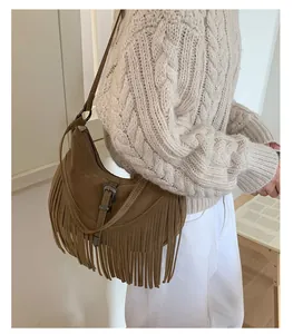 Gros plan du sac en daim marron avec longues franges et boucle argentée vintage