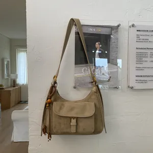 Detail of khaki suede hobo bag featuring external buckle pocket and beaded tassel