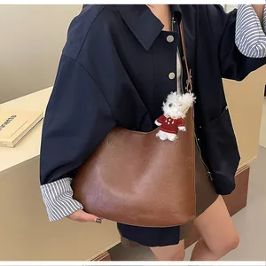 Detail view of large brown hobo bag with textured leather and cute puppy charm