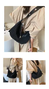 Detail of black leather hobo bag with wide grommet strap and decorative bag charms