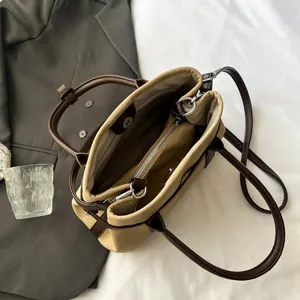 Minimalist canvas tote bag with brown leather straps and inner zipper pocket shown on suit