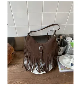 Détail d'un sac demi-lune en daim marron avec des franges bohèmes et une boucle rétro