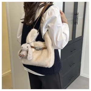 Detail van beige pluche emmertas met schattige konijnenpop en lederen riem