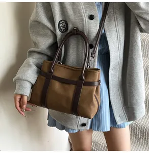 Detail of a brown canvas tote bag with leather trim and adjustable shoulder strap