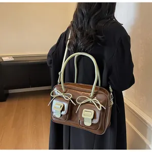 Detail of Boston bag with chocolate patent leather and green bow accents