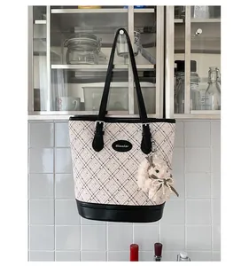Quilted tote bag with plush bunny charm hanging on a modern stainless steel rack