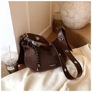 Retro dark brown matte leather dumpling bag with wide eyelet strap and side pendant