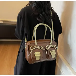 Detail view of a vintage brown leather bag with light green handles and bow accents