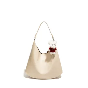 Minimalist beige hobo tote bag for women with a cute bear charm on a white background