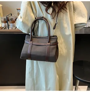 Detail of canvas and brown leather tote showing reinforced stitching and metal hooks