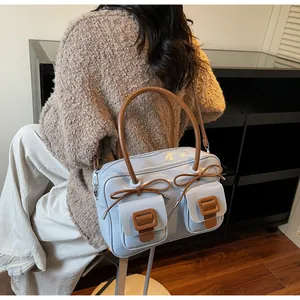 Close-up of light blue glossy handbag with brown bow details and decorative pockets