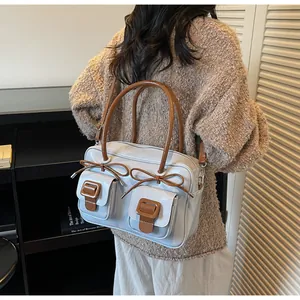 Detail of light blue patent leather shoulder bag with bow and double front pockets