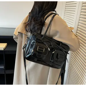 Detail of a black patent leather shoulder bag with bow accents and dual flap pockets