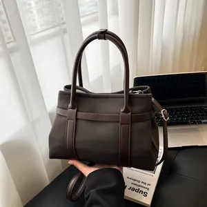 Dark brown canvas tote bag with leather handles shown in a professional office setting