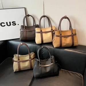 Minimalist canvas tote bags with leather trim in five colors displayed on a sofa