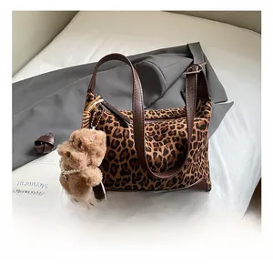 Detail of vintage leopard print suede handbag with brown leather handle and plush bear charm