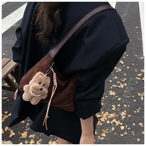 Detail of retro brown suede shoulder bag featuring a cute teddy bear charm with pearls