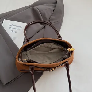Brown suede bowling bag with leather handles and interior pocket shown from a top view