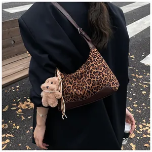 Detail view of leopard print shoulder bag with brown leather trim and tassel charm
