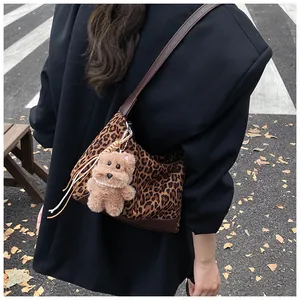 Detail view of leopard print shoulder bag with plush puppy pendant and long leather straps