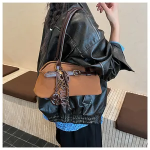 Detailed side view of a brown suede hobo bag with leather straps and decorative charms