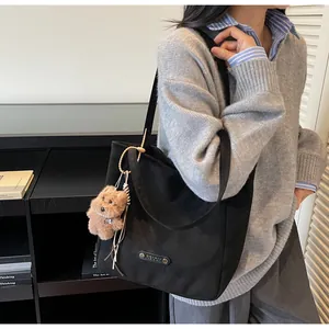 Close-up of black tote bag with matte texture and a cute brown puppy plush charm detail