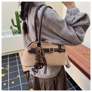 Close-up of beige suede bowling bag with brown leather straps and metal charms