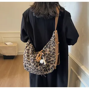 Detail of leopard print plush hobo bag with adjustable brown strap and cute bag charms