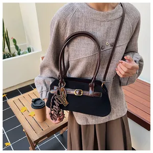 Detail of vintage black suede handbag with brown leather straps and gold metal buckles