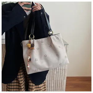 Detail of bohemian laser-cut floral suede tote with ethnic tassel and leather straps