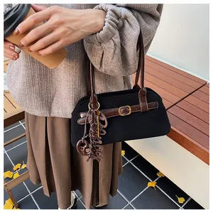 Macro shot of black suede shoulder bag with brown leather strap and decorative charms