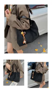 Detail of black suede tote bag with laser-cut patterns and ethnic tassel charm