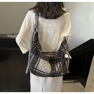 Detail of grey plaid wool crossbody bag featuring a soft texture and baseball pendant